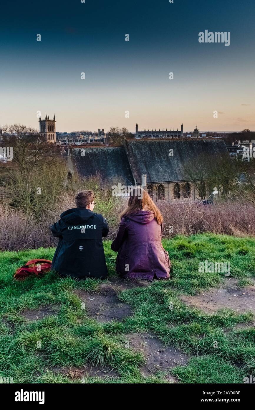 Dos personas sentadas en Castle Mound mirando la vista de Cambridge. Una persona tiene chaqueta universitaria con Cambridge en la parte de atrás. Foto de stock
