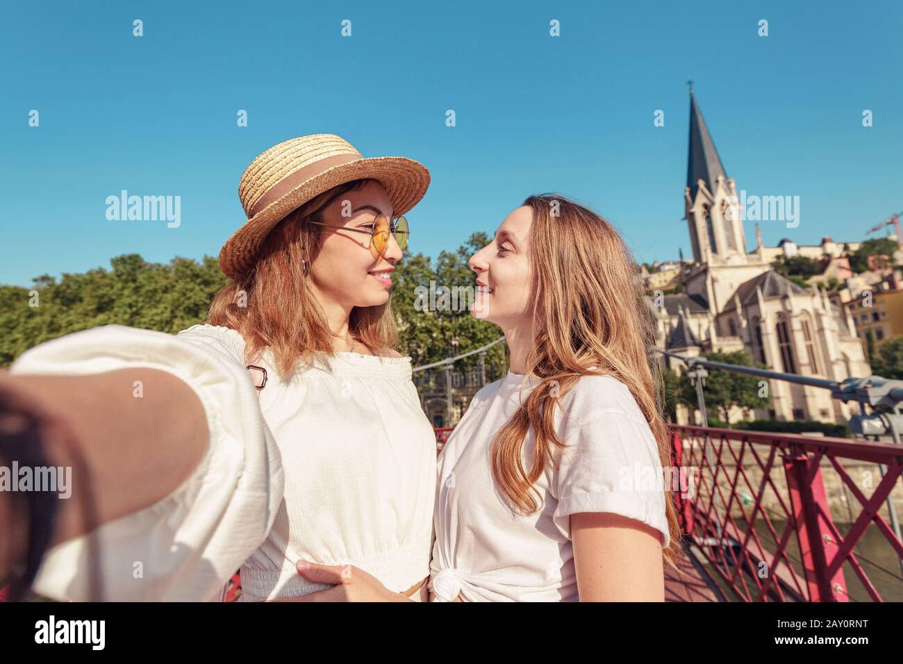 Dos amigas felices caminando por el puente peatonal de Saint Georges mientras viajaban por el casco antiguo de Lyon en Francia Foto de stock
