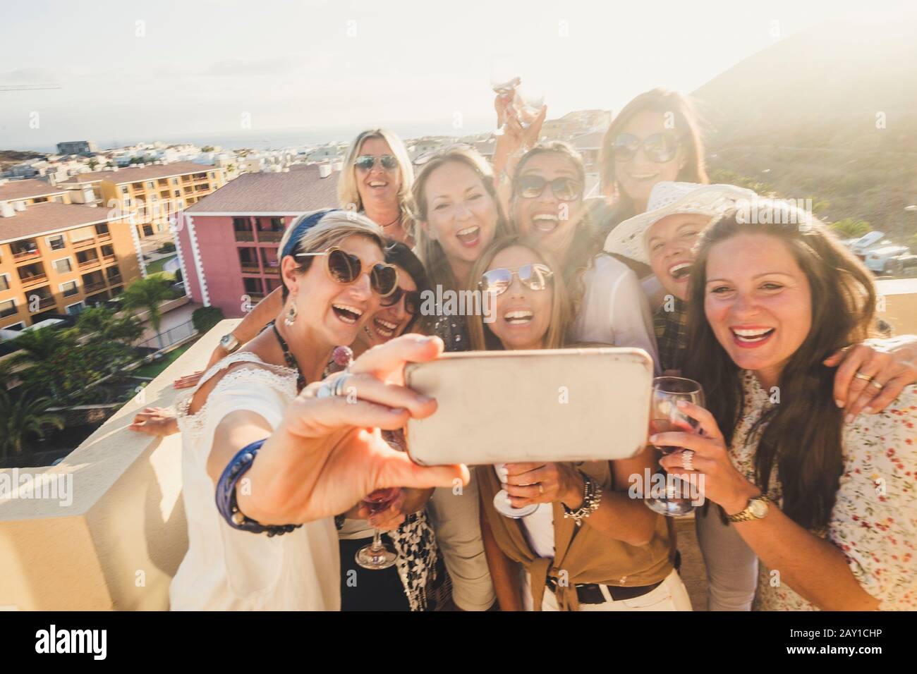 Grupo de mujeres jóvenes felices y alegres se divierten en la fiesta juntos al aire libre tomando la foto selfie con el teléfono - la gente celebra con vino y tostar Foto de stock