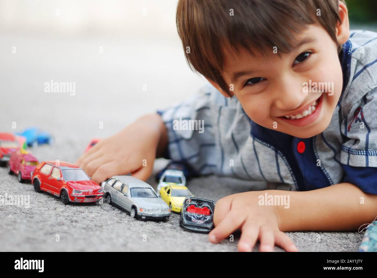 Un niño pequeño está acostado y jugando con los coches Foto de stock