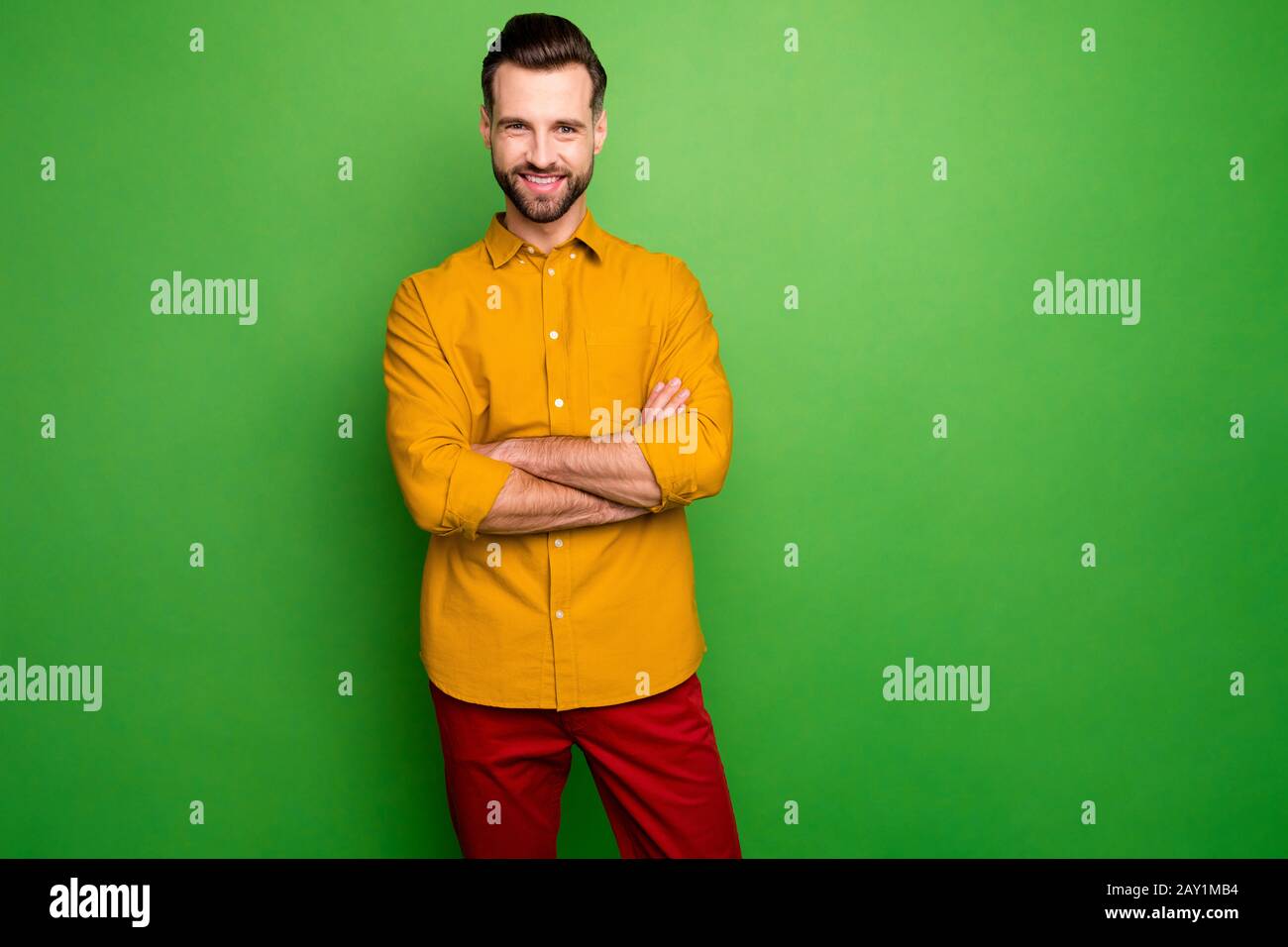 Foto de guapo joven hombre de negocios bossy cruzó los amistoso Toothy sonriente compañeros de ropa camisa amarilla pantalón rojo aislado verde Fotografía de stock - Alamy