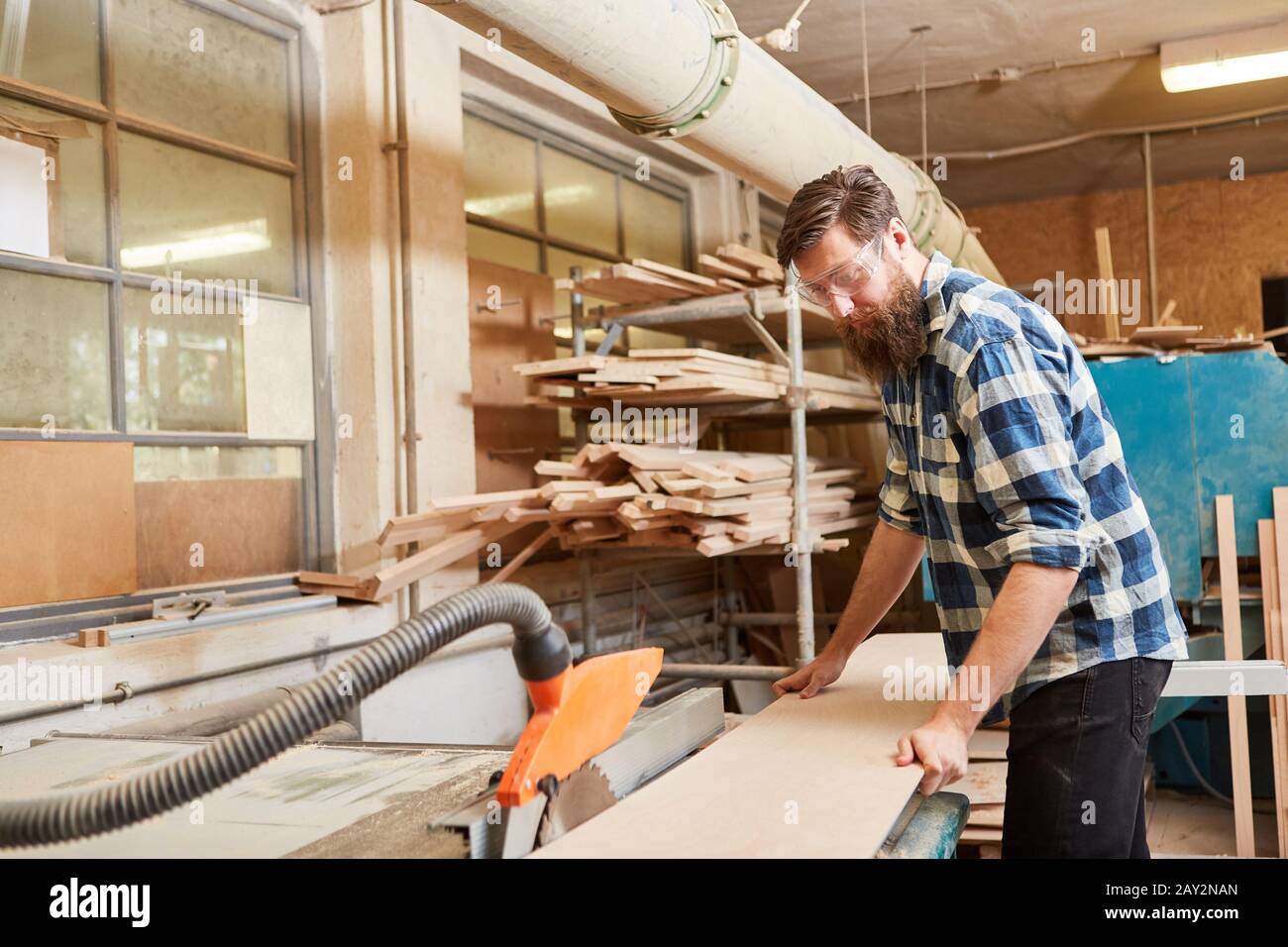 Carpenter trabaja con la sierra circular en el taller de carpintería Foto de stock