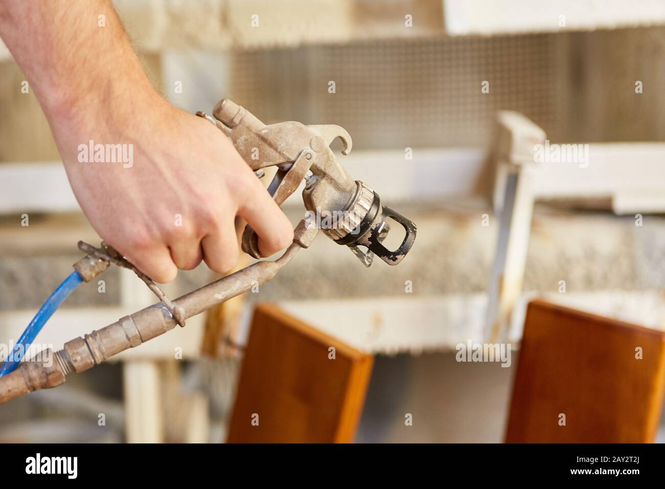 Mano de carpintero mientras pintan madera con la pistola de pulverización o pistola de pintura Foto de stock
