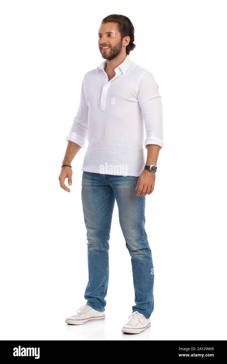 Un hombre guapo con jeans, zapatillas de deporte y camisa blanca se  mantiene relajado, mirando y sonriendo. Estudio de gran longitud con  disparo aislado en blanco Fotografía de stock - Alamy
