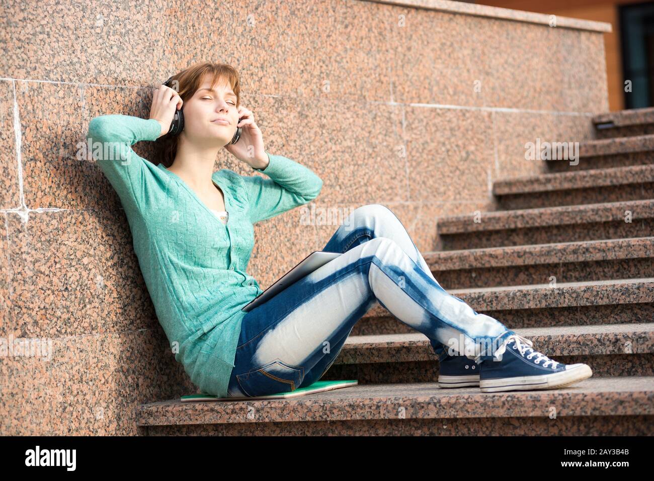 Hermosa joven estudiante con auriculares. Niña de música al aire libre Foto de stock