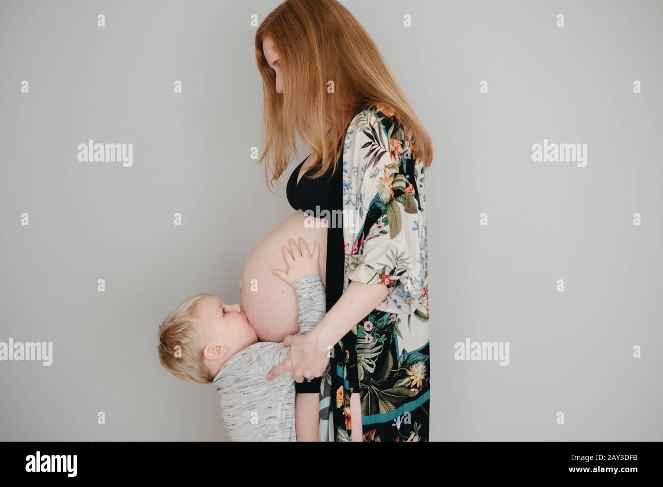 Niño besando a las madres vientre Foto de stock