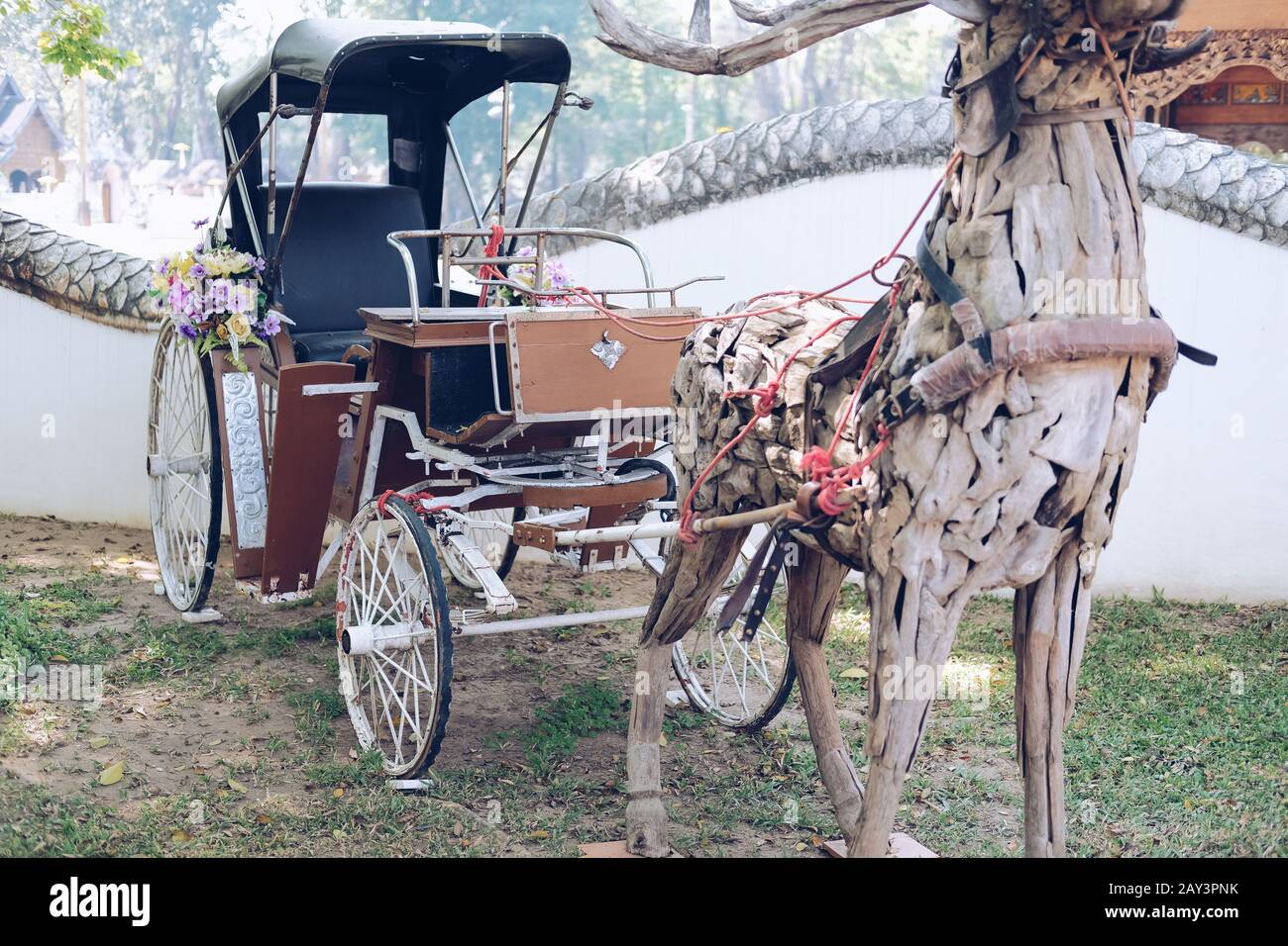 antiguo triciclo asiático retro y ciervos de madera decorando en el parque Foto de stock
