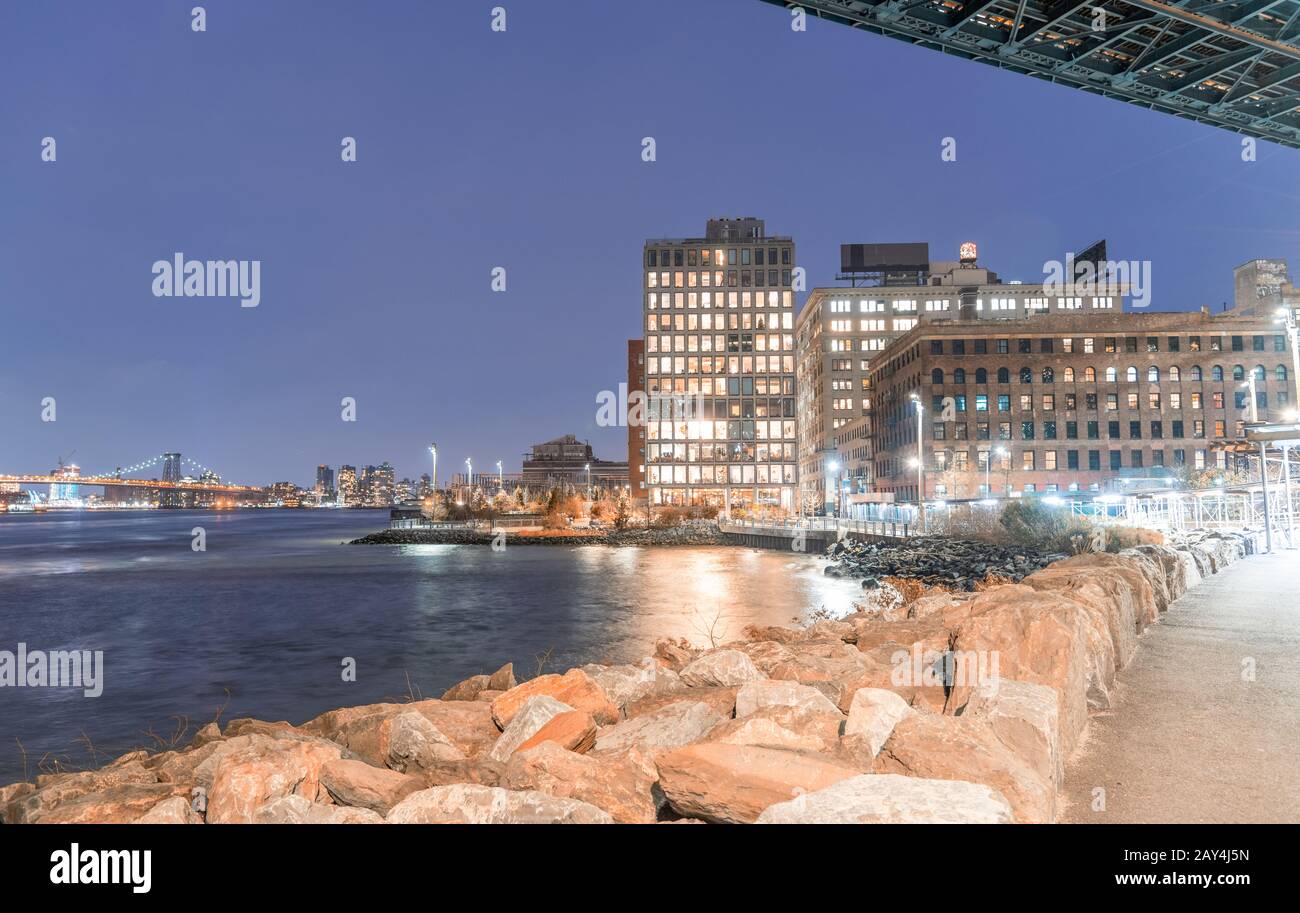 Vista de los edificios de Brooklyn desde debajo de Manhattan Nridge por la noche. Williamsburg Puente sobre el fondo. Foto de stock