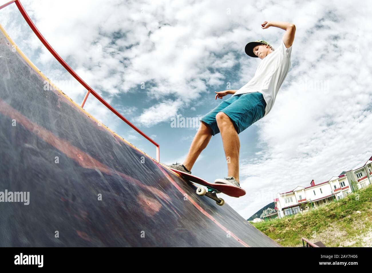 Un patinador adolescente cuelga sobre una rampa en una tabla de skate en un parque de skate Foto de stock