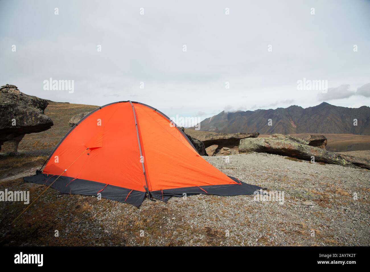 Una carpa naranja de gran altitud está situada en lo alto de las montañas, sobre el fondo de la cresta caucásica Foto de stock