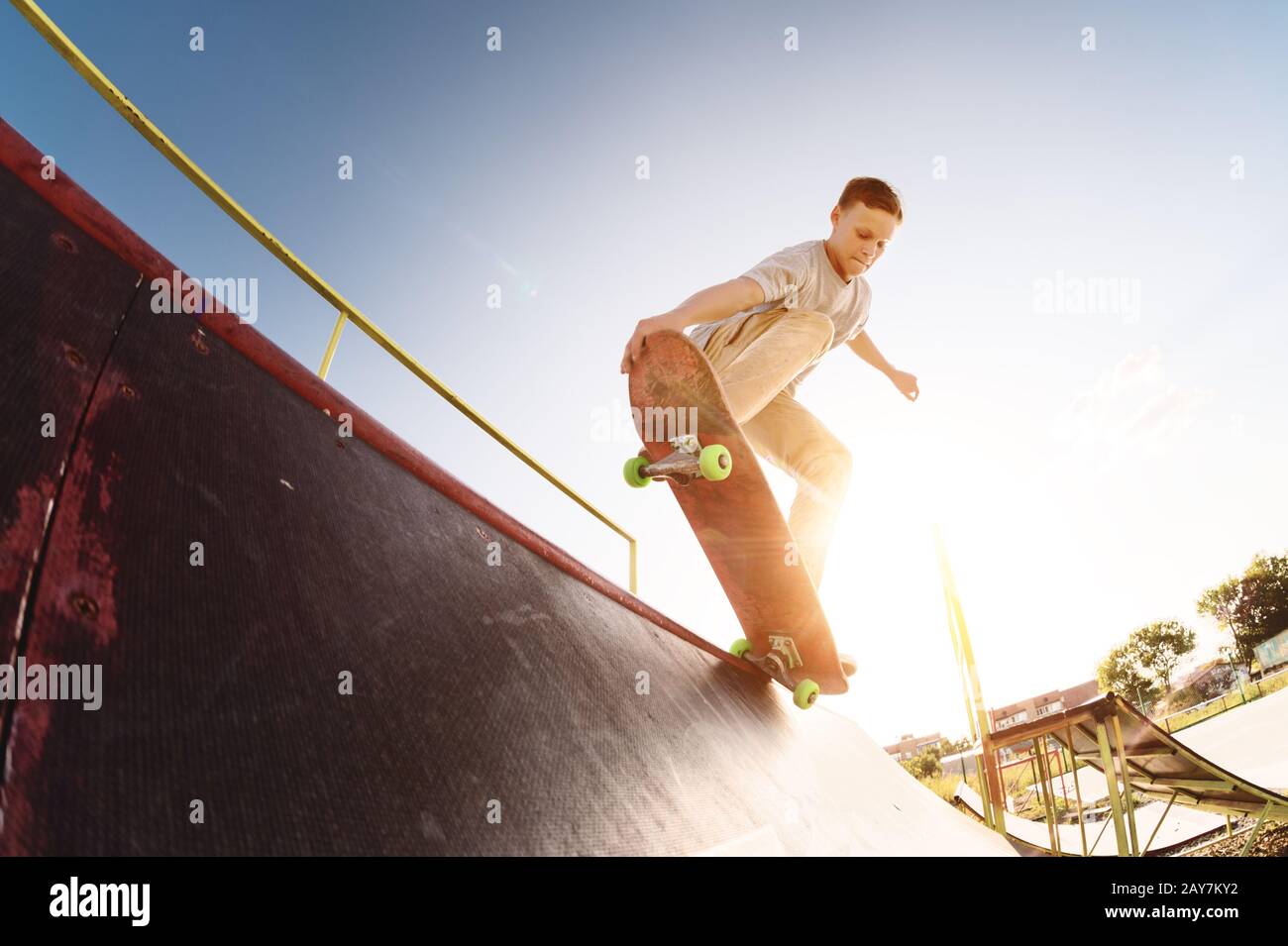 Un patinador adolescente cuelga sobre una rampa en una tabla de skate en un parque de skate Foto de stock