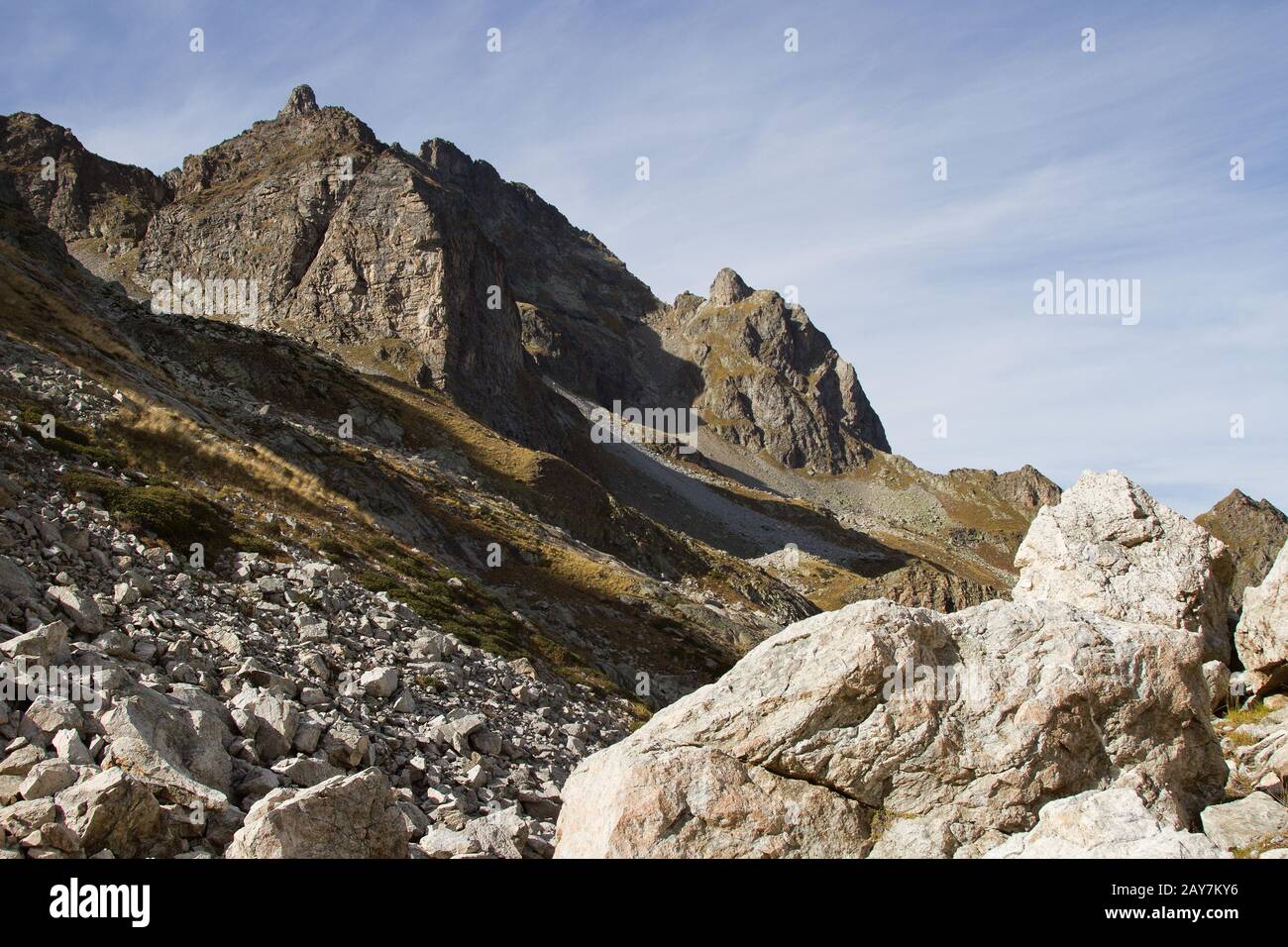 Rocas agudas de alta montaña contra el cielo azul y las nubes blancas. Cáucaso Foto de stock