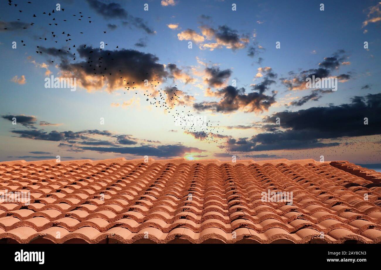 Techo De Azulejos De Arcilla Roja Bajo Un Cielo De Puesta De Sol Foto de stock