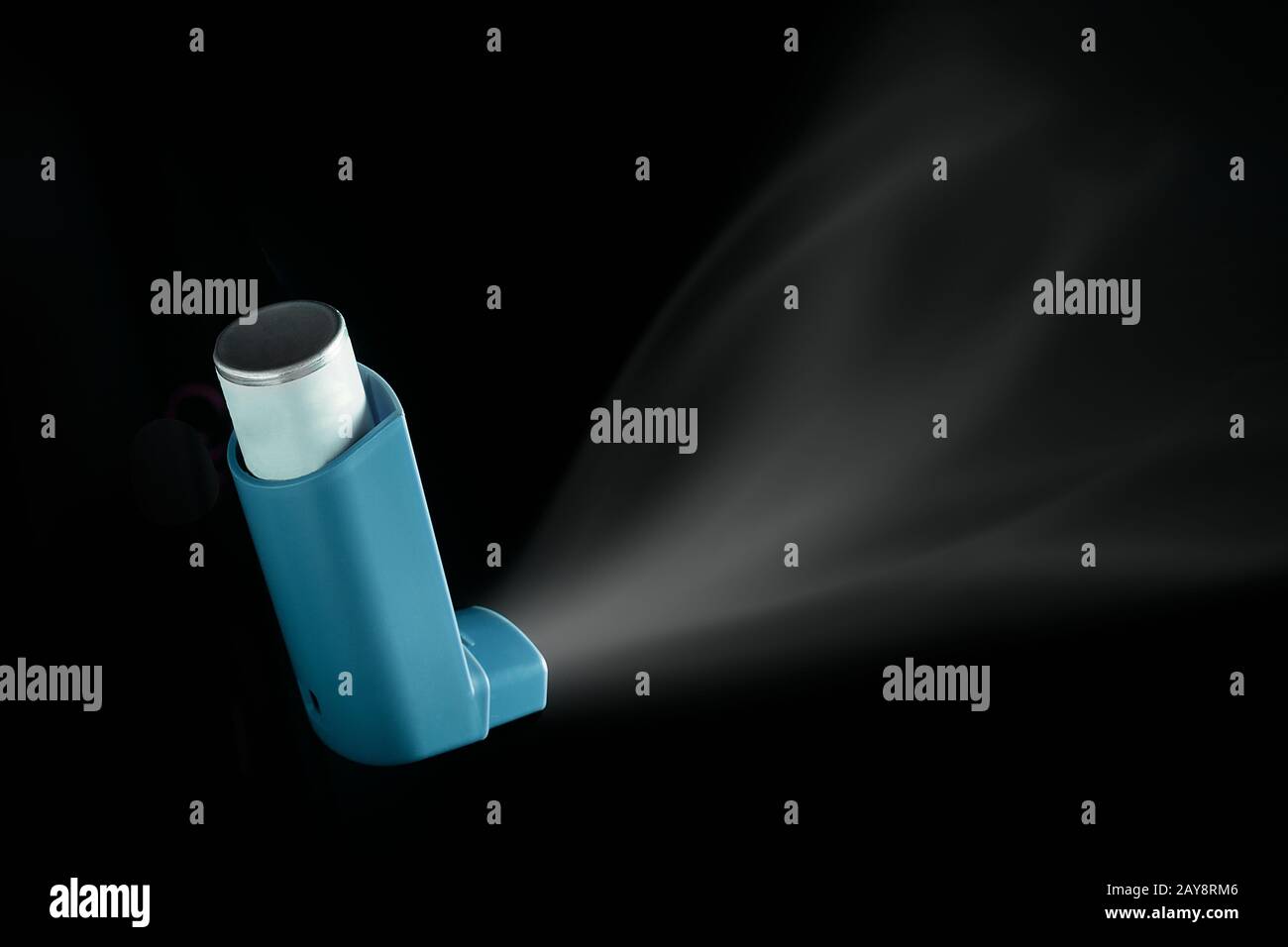 Inhalador MDI empujado sobre fondo negro. Aerosol de asma para personas con problemas respiratorios Foto de stock