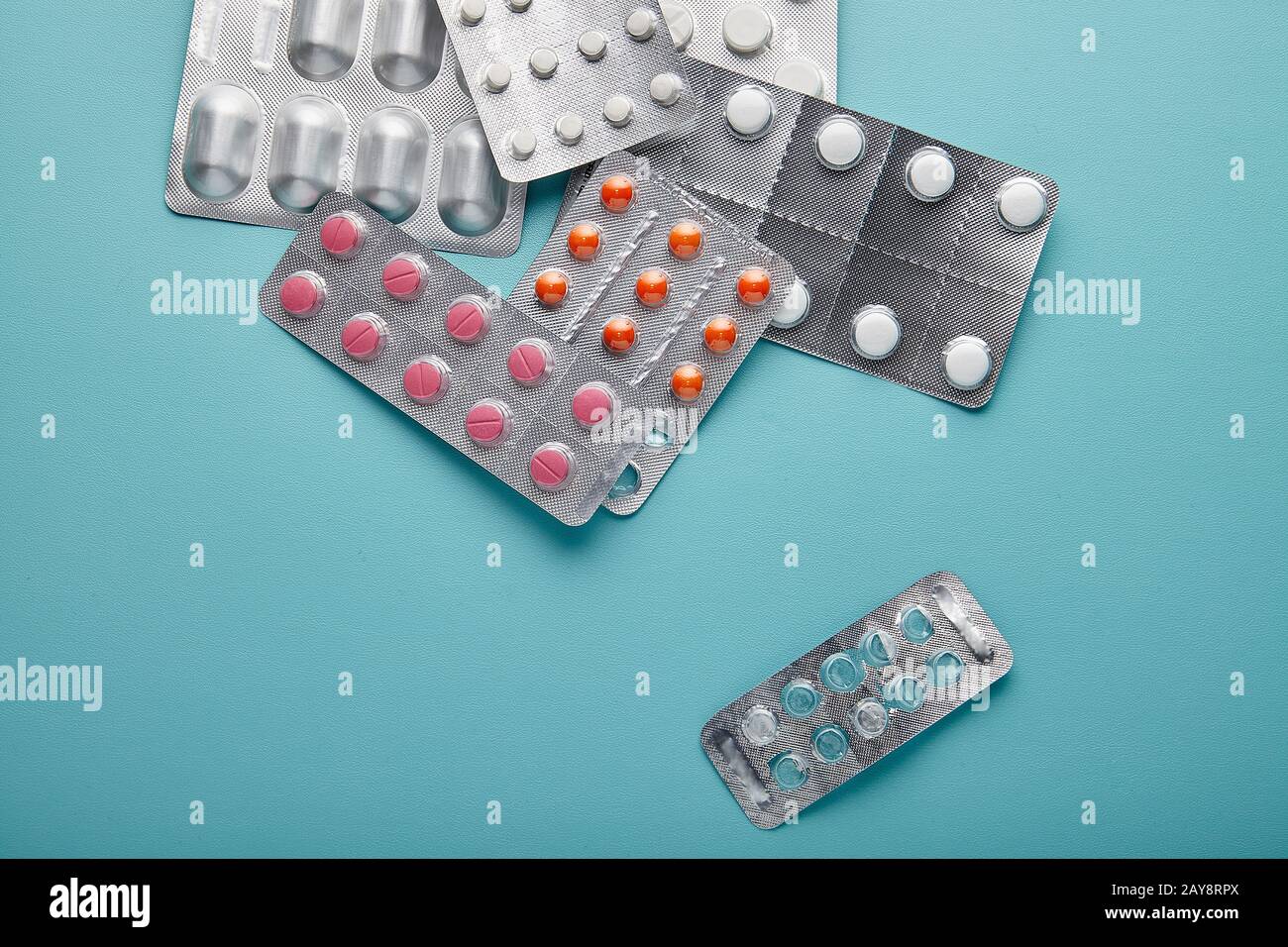 Diferentes pastillas de medicina apiladas envolvientes sobre fondo azul cielo. Vista Superior Foto de stock
