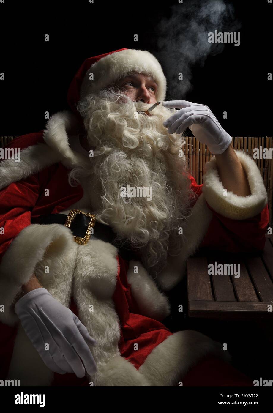 Santa Claus necesita un pequeño descanso y fuma un cigarrillo. Temporada de Navidad y adviento estresante. Foto de stock
