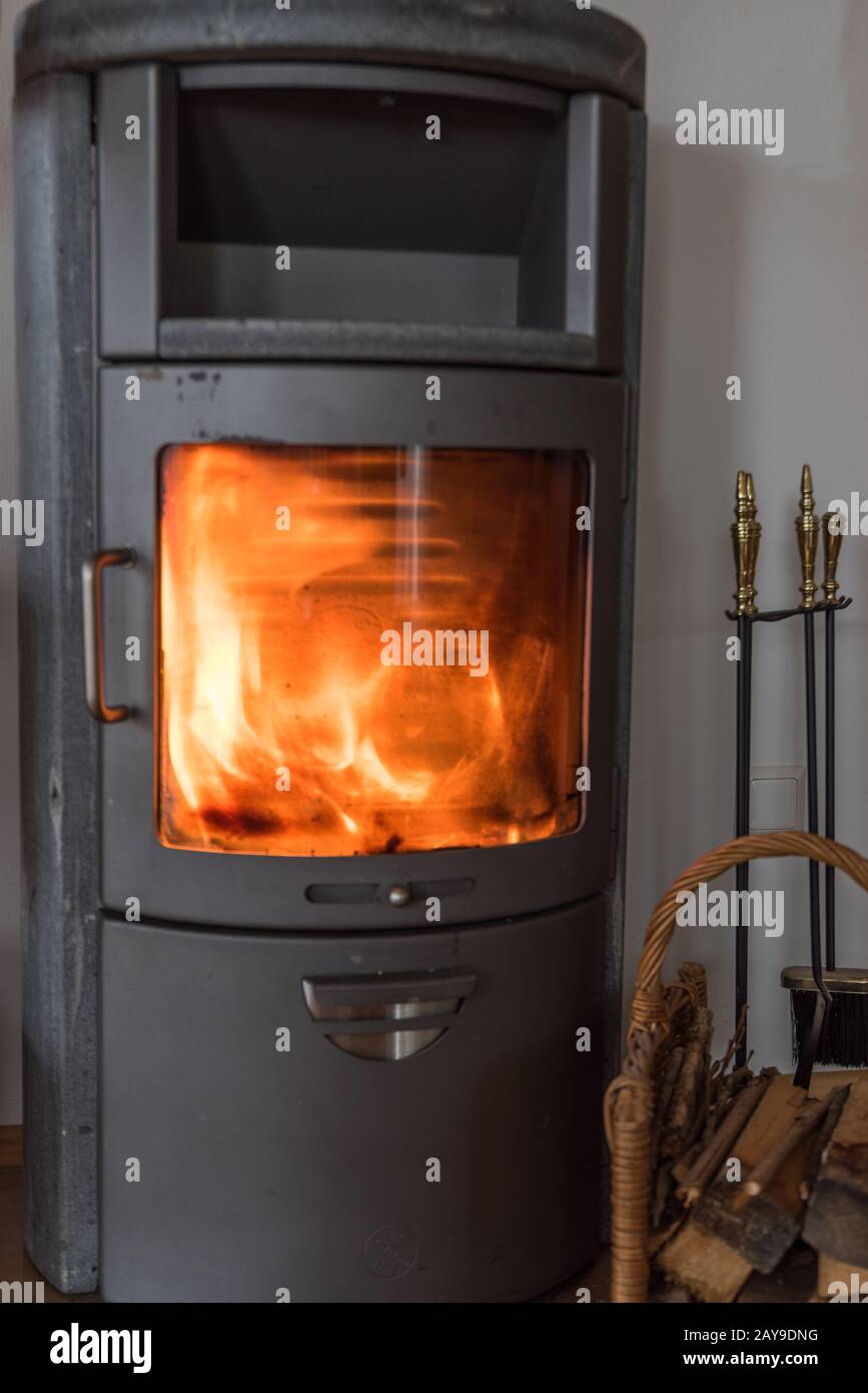 Fuego caliente con leña en la ventana de la nostálgica estufa de madera - madera de pedazo Foto de stock