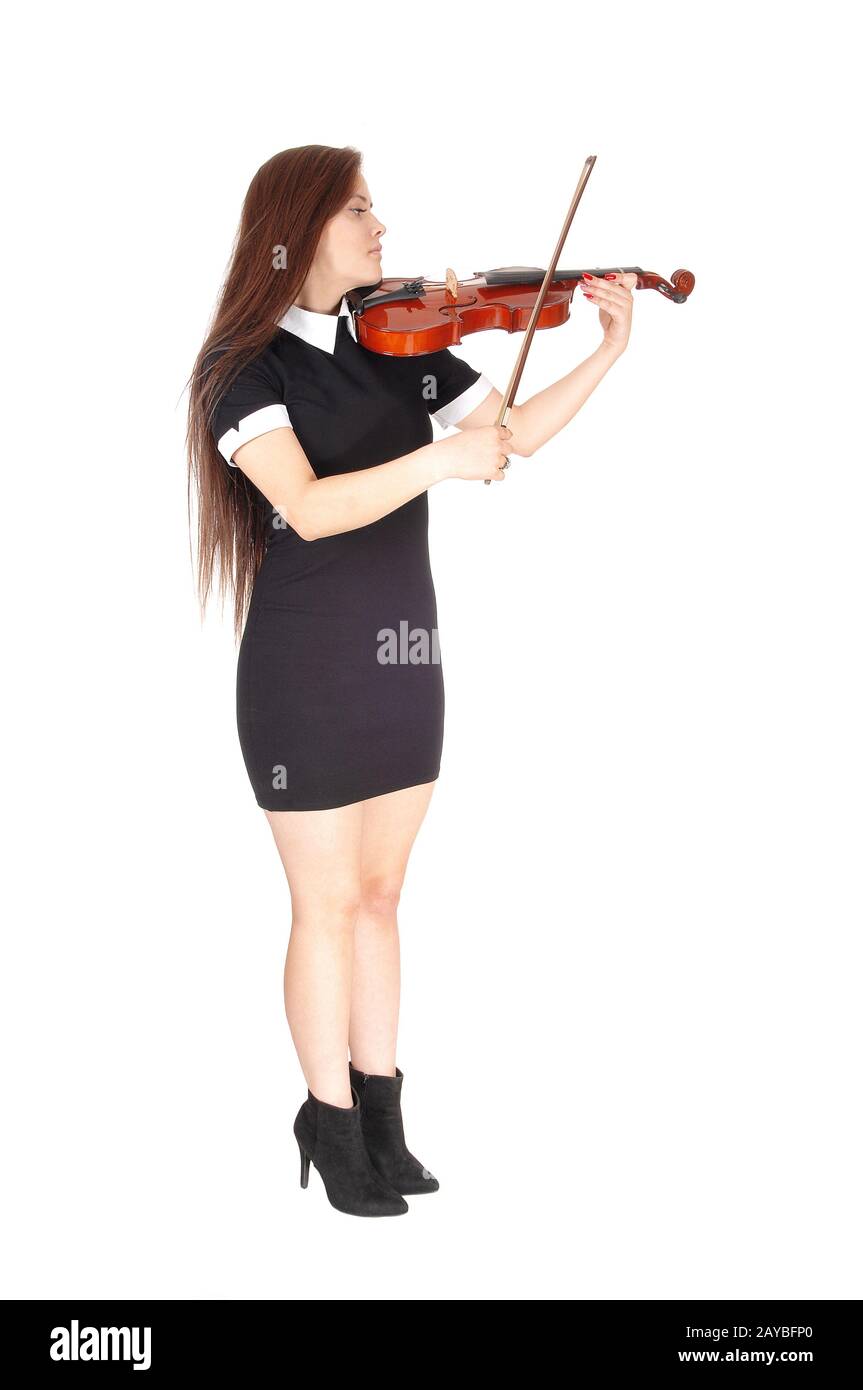 Una mujer de pie y tocando el violín con un vestido negro Foto de stock