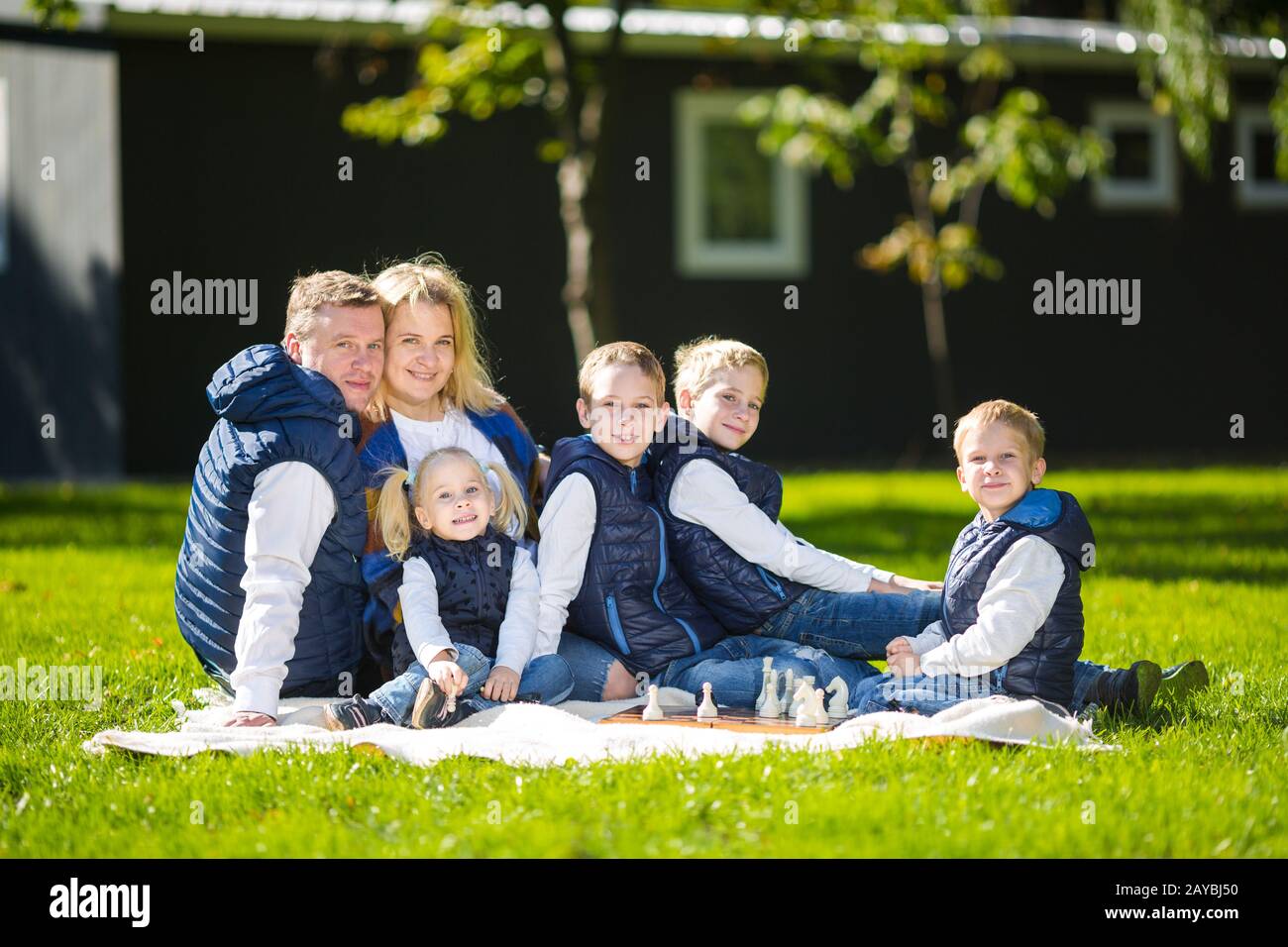 Gran Familia Relajante En La Naturaleza Verde. Feliz retrato familiar al aire libre, grupo seis personas se sientan en hierba, temporada de verano, niño y p Foto de stock