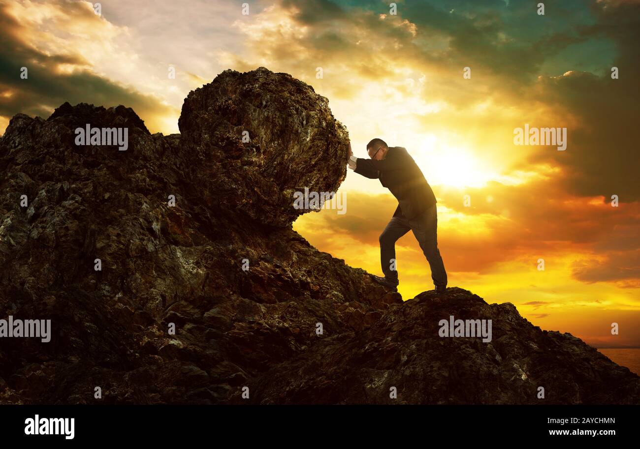 Hombre de negocios empujando piedra grande hasta la colina Foto de stock