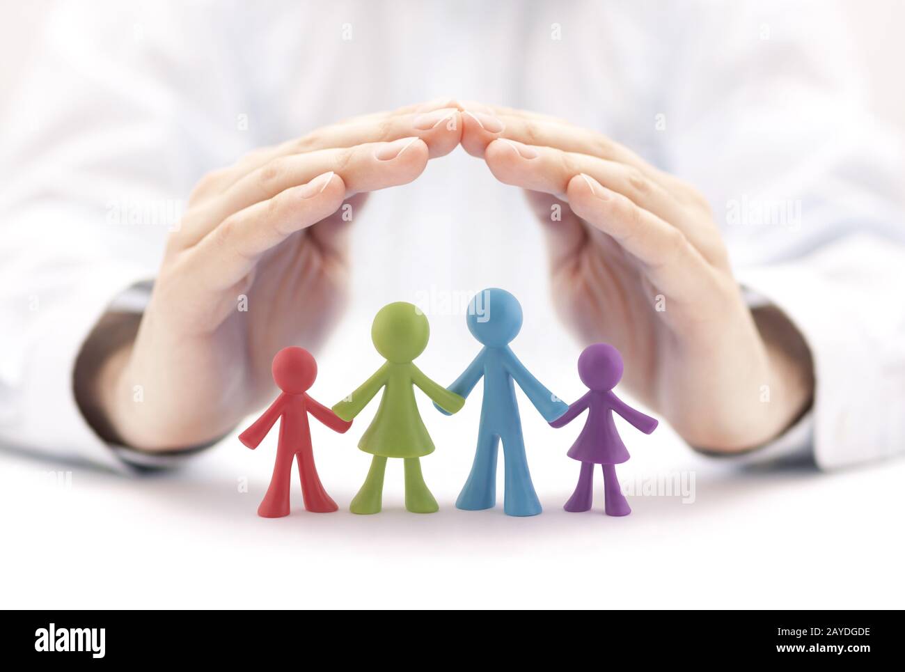 Concepto de seguro familiar con coloridas figuras familiares cubiertas de manos Foto de stock