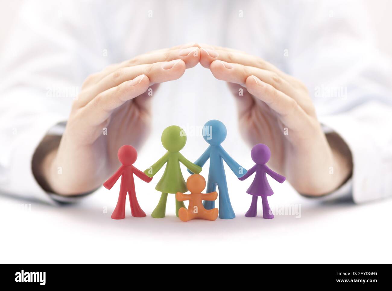 Concepto de seguro familiar con coloridas figuras familiares cubiertas de manos Foto de stock