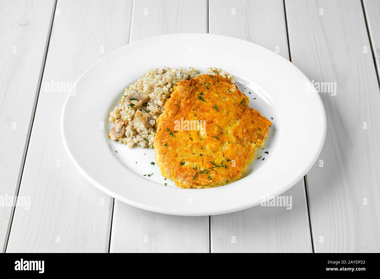 Schnitzel con trigo sarraceno verde sobre mesa de madera blanca Foto de stock