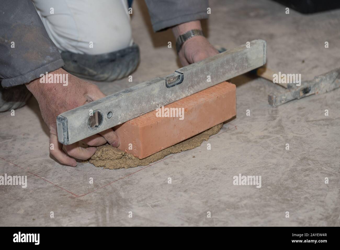 Bricklayer trabaja con ladrillo y mortero con la ayuda de un nivel de espíritu - primer plano Foto de stock