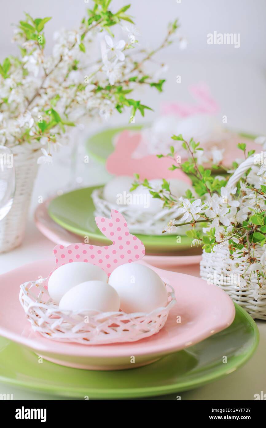 Felices pascuas. Decoración y el ajuste de la tabla de la mesa de Pascua es un jarrón con flores rosas tulipanes y platos de color verde y rosa. El enfoque selectivo. Foto de stock