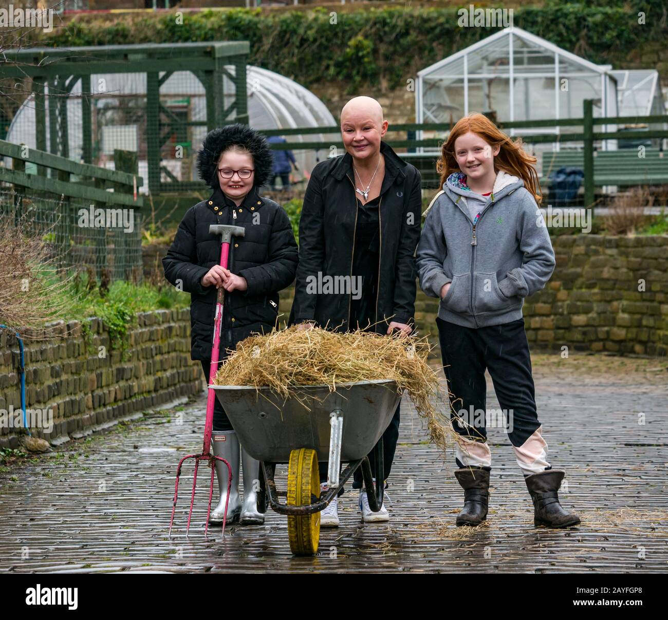 Edimburgo, Escocia, Reino Unido, 15 De Febrero De 2020. Granja de la ciudad de Gorgie: Gail Porter, que tiene recuerdos de la infancia de visitar la granja se encuentra con el NUEVO AMOR Gorgie Farm para ayudar a los voluntarios a preparar la granja para la apertura. Love Learning, una organización benéfica de educación y asistencia social que apoya a las personas vulnerables anunció su toma de control de la granja de la ciudad en enero de 2019. La granja volverá a abrir sus puertas el 29 de febrero de 2020. Foto: Gail con Scarlet (9 años y Myla (11 años) que se ofrecen como voluntarios en la granja Foto de stock