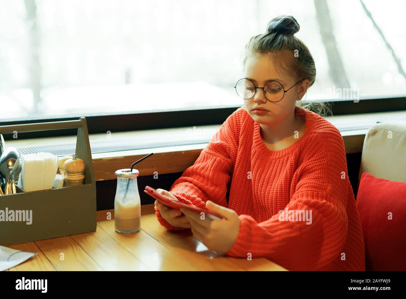 Niña adolescente sentada en una cafetería a la espera de una mesa Foto de stock