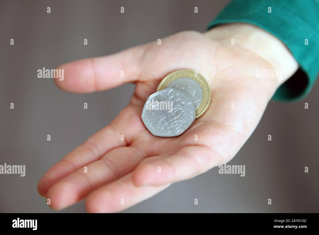 Un niño tiene £2.50 en su mano con un Kew Gardens 50p en cambio y una moneda de £2 Foto de stock