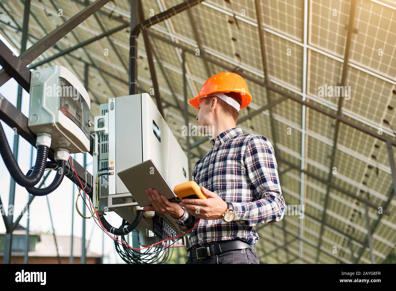 Un ingeniero masculino con un ordenador portátil configura el equipo en la central solar. Ecología concepto de ahorro de energía. Generación de energía ecológica verde. Foto de stock