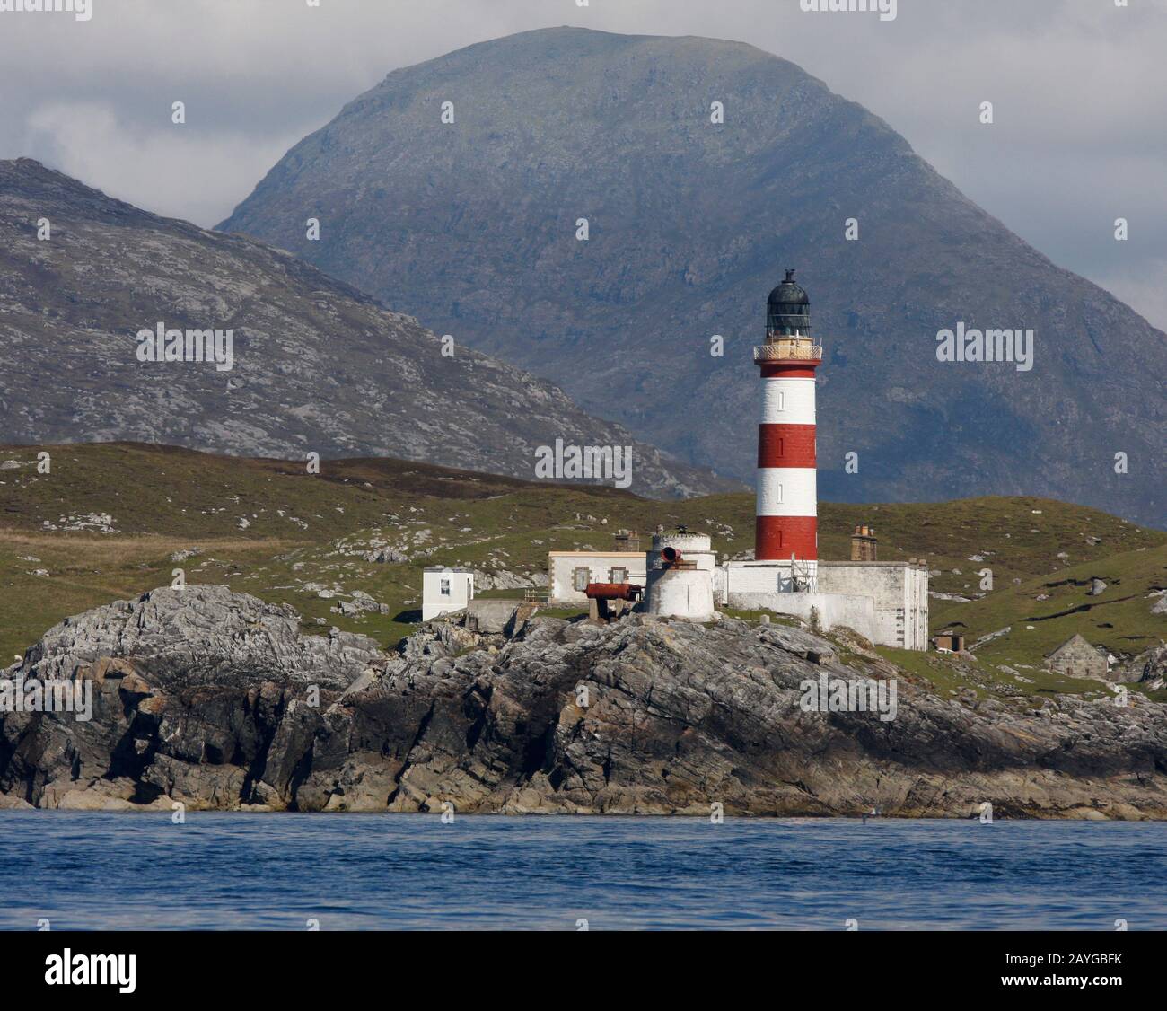 El faro alto, rojo y blanco rayado de las Glas Eileas, Scalpay, desde el mar, con las colinas de Harris detrás, las Western Islands, Escocia Foto de stock