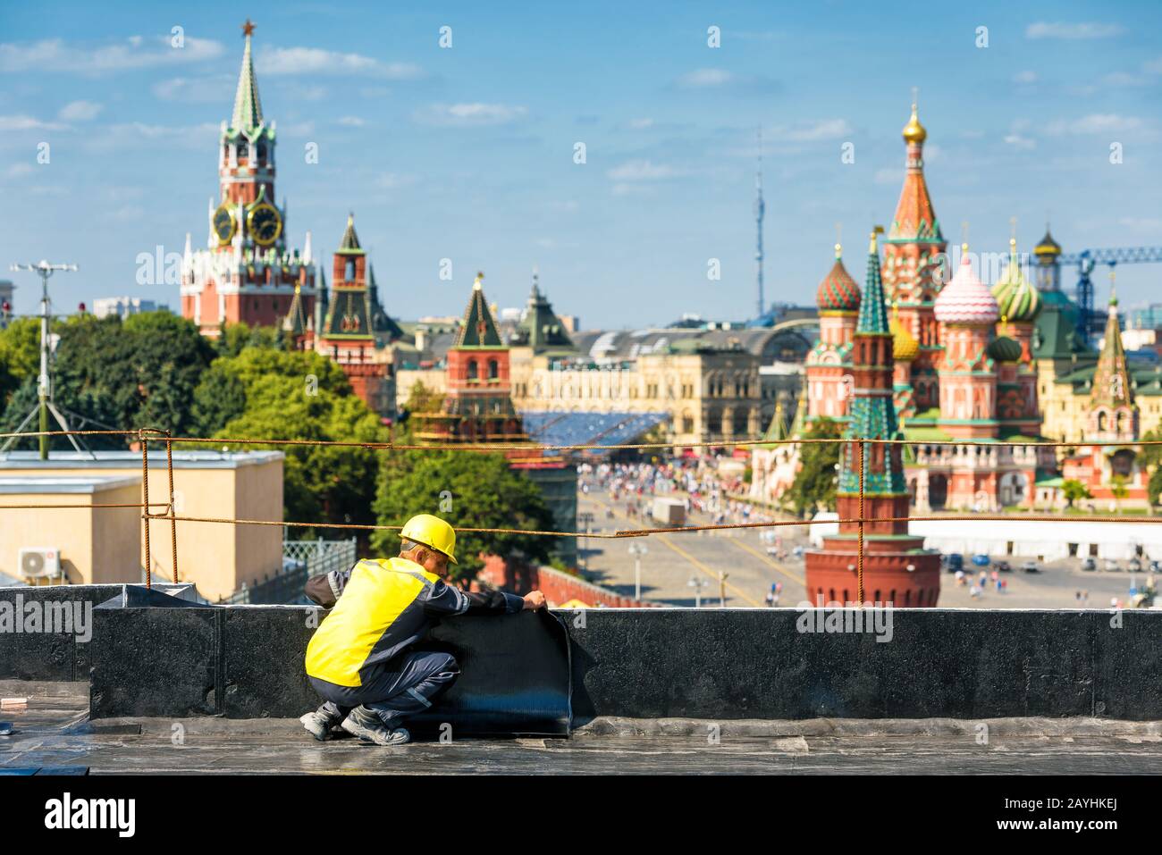 Moscú, Rusia - 10 de agosto de 2017: El trabajador trabaja en una obra en el centro de Moscú. Kremlin de Moscú y Catedral de San Basilio en el b Foto de stock