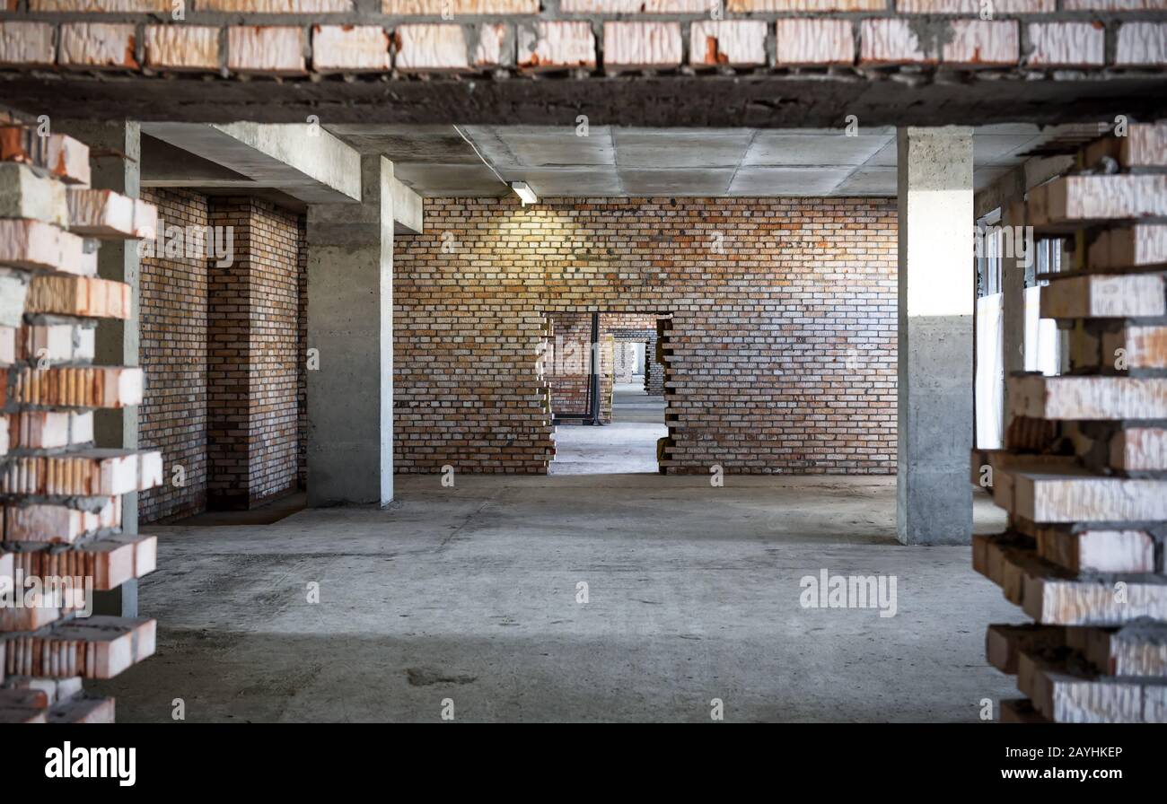 Piso en un edificio en construcción, columnas de concreto y paredes de ladrillo con puerta Foto de stock