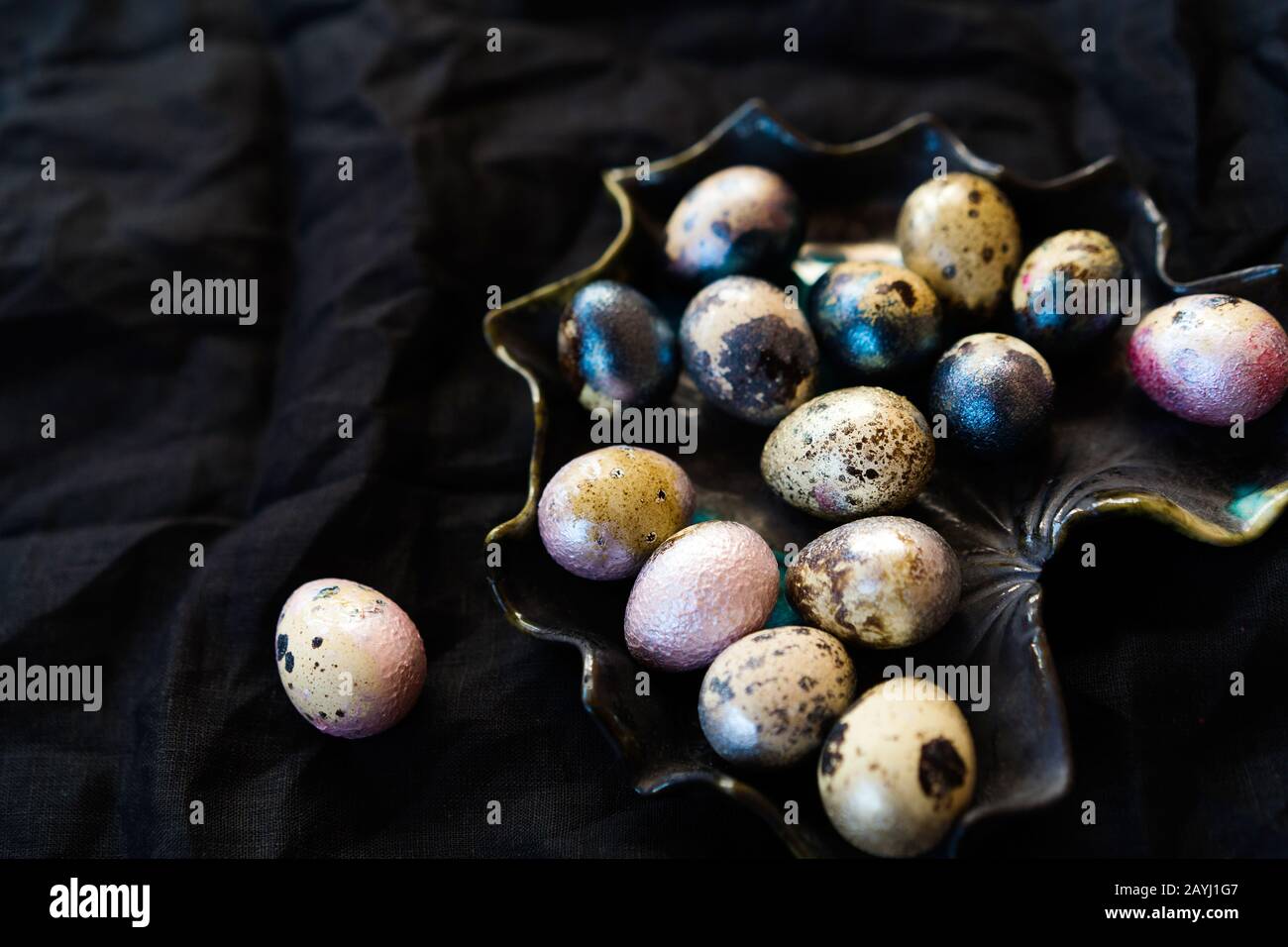Huevos de pollo y codorniz de color rosa, plateado, dorado y azul sobre negro Foto de stock
