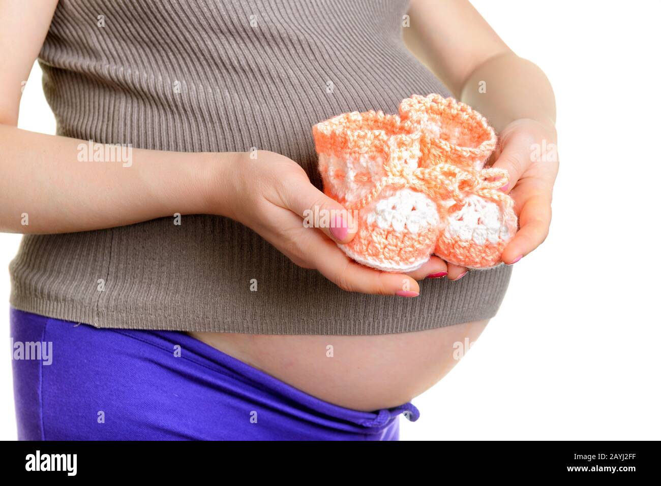 Mujer embarazada que sostiene un hermoso bebé zapatos de lana aislado en blanco Foto de stock