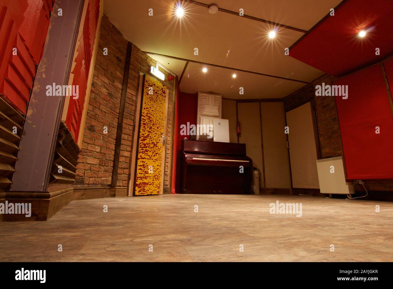 Sala vacía en el estudio de grabación con paredes rojas y piano vertical. Producción musical y espacio de trabajo para productores de discos Foto de stock