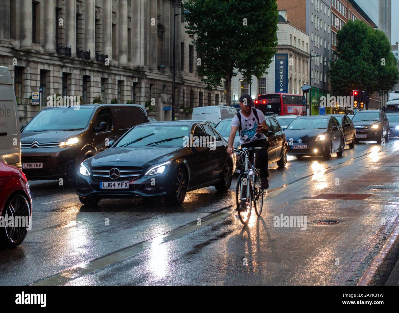 Tráfico De Londres, Jam, Euston Road, Lloviendo, Ciclista, En El Móvil, Sin Semáforos, Dusk, Londres, Inglaterra Foto de stock