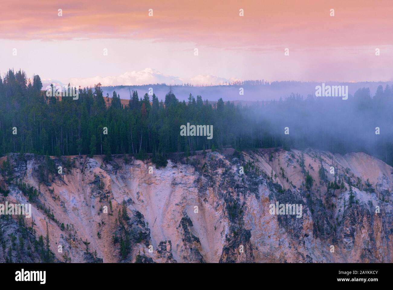 Puesta de sol sobre bosque brumoso en el cielo de montaña bajo el cielo naranja pastel. Foto de stock