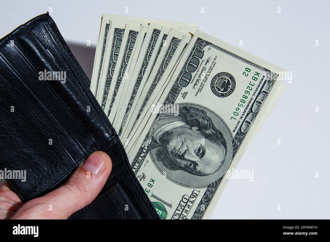 Feliz joven hombre de negocios tiene una cartera en su mano con dinero.  billetes de 100 dólares en una cartera de cuero negro Fotografía de stock -  Alamy