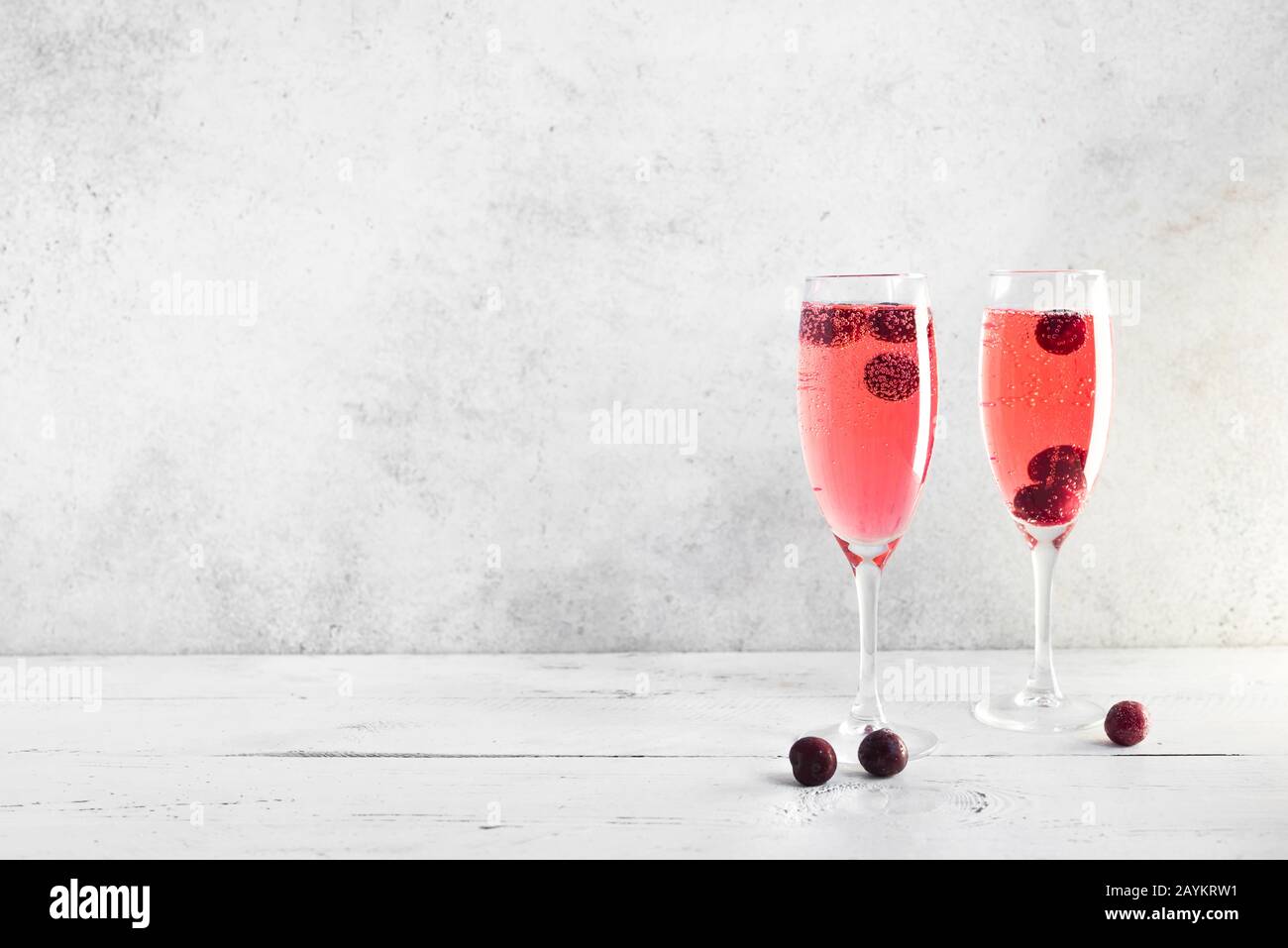 Cóctel de champán Kir Royal en blanco, espacio para copiar. Copas de flauta con champán espumoso berry para celebrar o relajarse. Foto de stock