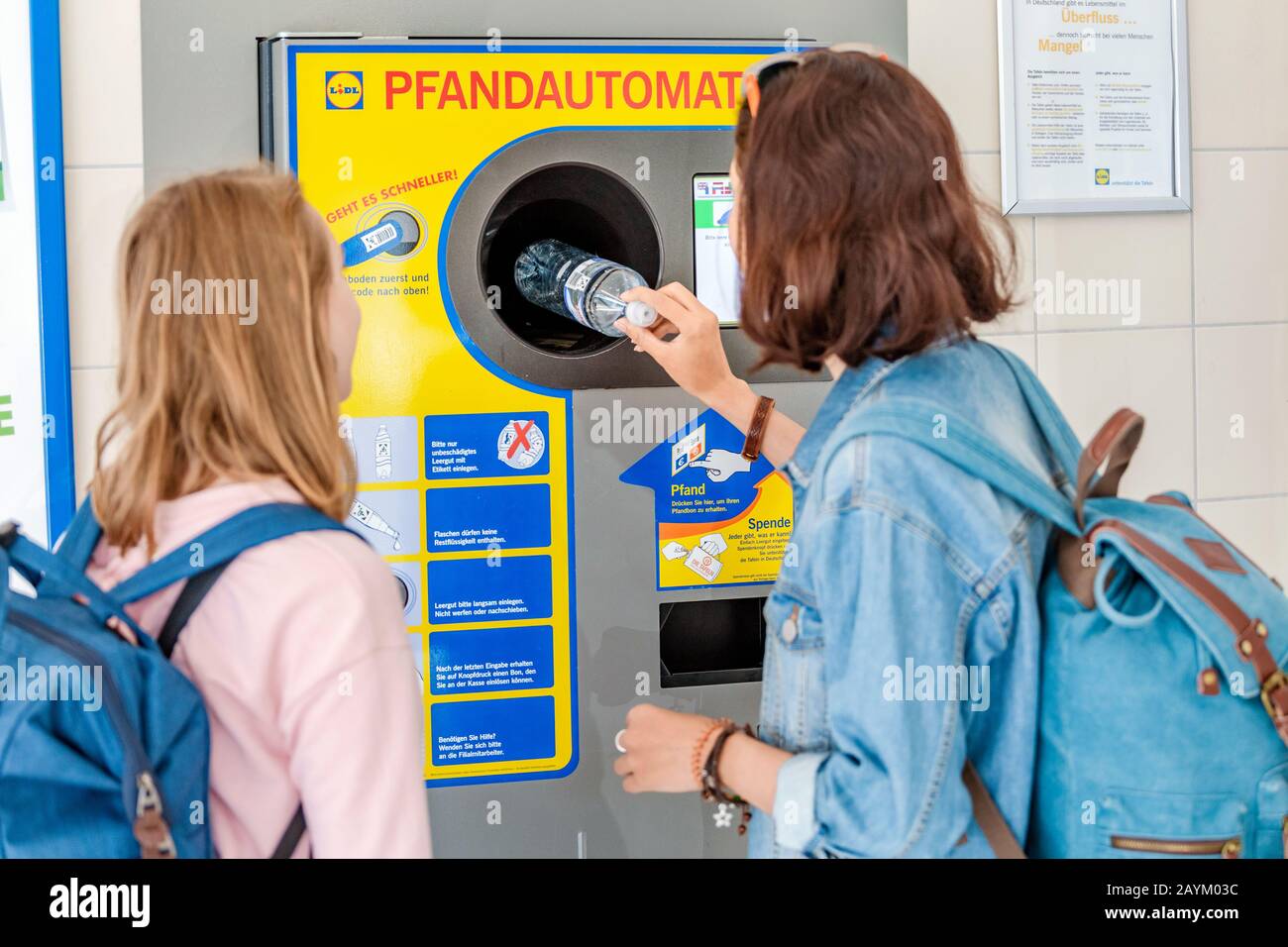 22 DE MAYO de 2018, LEIPZIG, ALEMANIA: Mujeres amigas juntas en la máquina expendedora inversa reciclan botellas de plástico, concepto ecológico Foto de stock