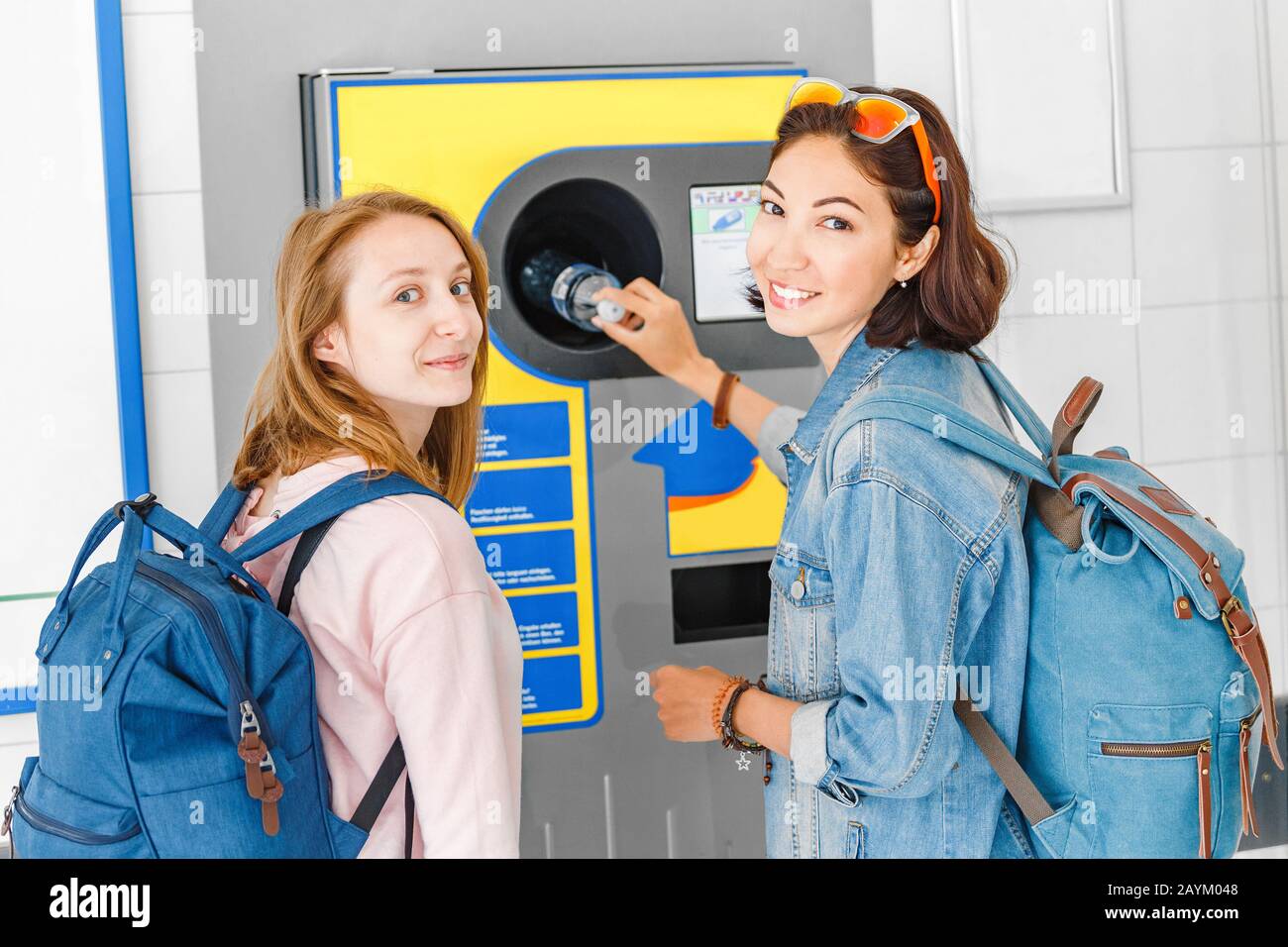 Mujeres amigas juntas en la máquina expendedora inversa reciclan botellas de plástico, concepto ecológico Foto de stock