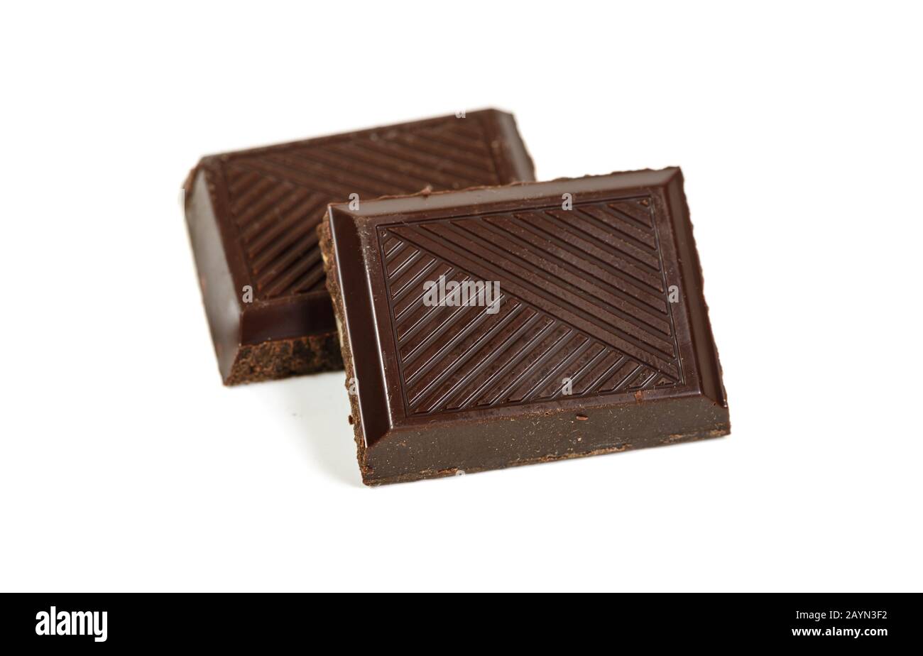Un par de barras de chocolate rotas de pieza oscura aisladas sobre una vista macro blanca Foto de stock