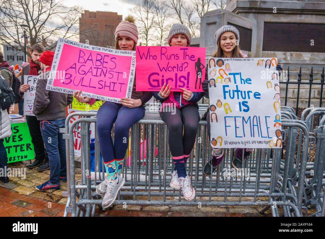 20 de enero de 2018-Cambridge, MA, EE.UU.- Tres niñas llevan señales de protesta en el Primer Aniversario de la marcha de las mujeres. Foto de stock