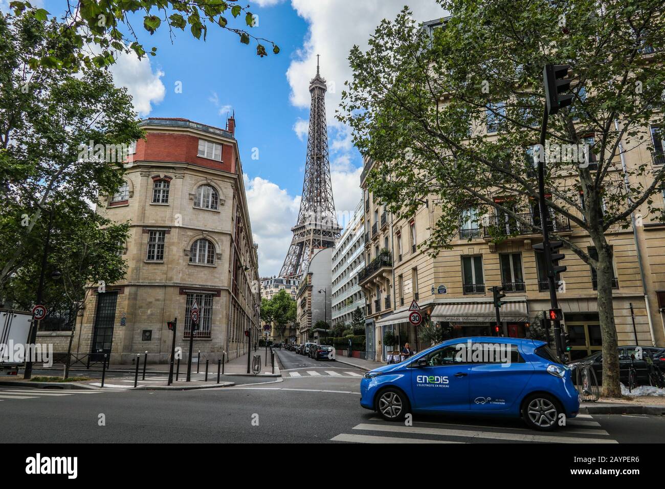 Escena callejera con el coche eléctrico Endis y la Torre Eiffel al fondo París, Francia, Europa Foto de stock