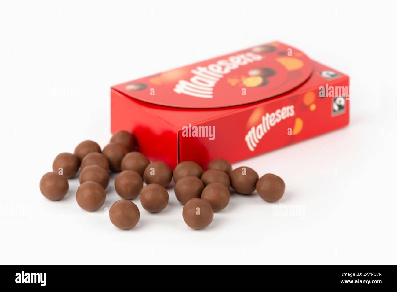 Algunos chocolates Maltesers se rodaron sobre un fondo blanco junto con el embalaje de la caja del producto. Foto de stock