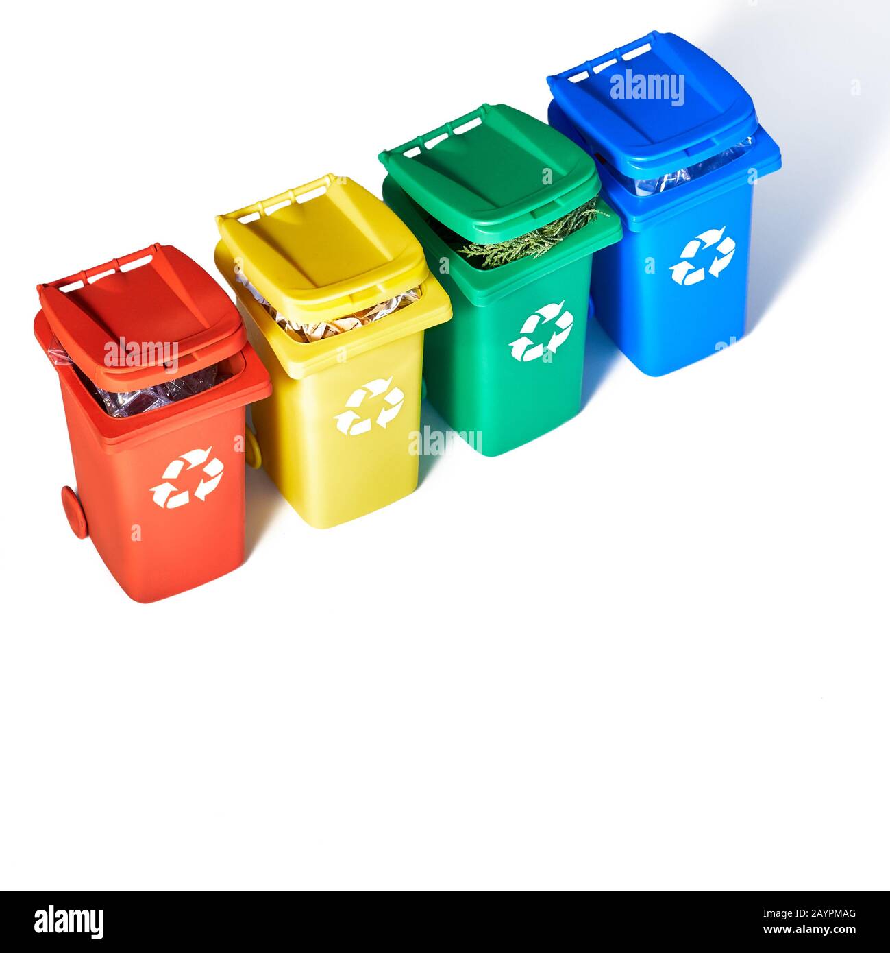 Cuatro contenedores de reciclaje codificados por colores, proyección  isométrica sobre fondo de papel arco iris geométrico con espacio de copia.  Signo de reciclaje en los contenedores - rojo, azul, amarillo Fotografía de